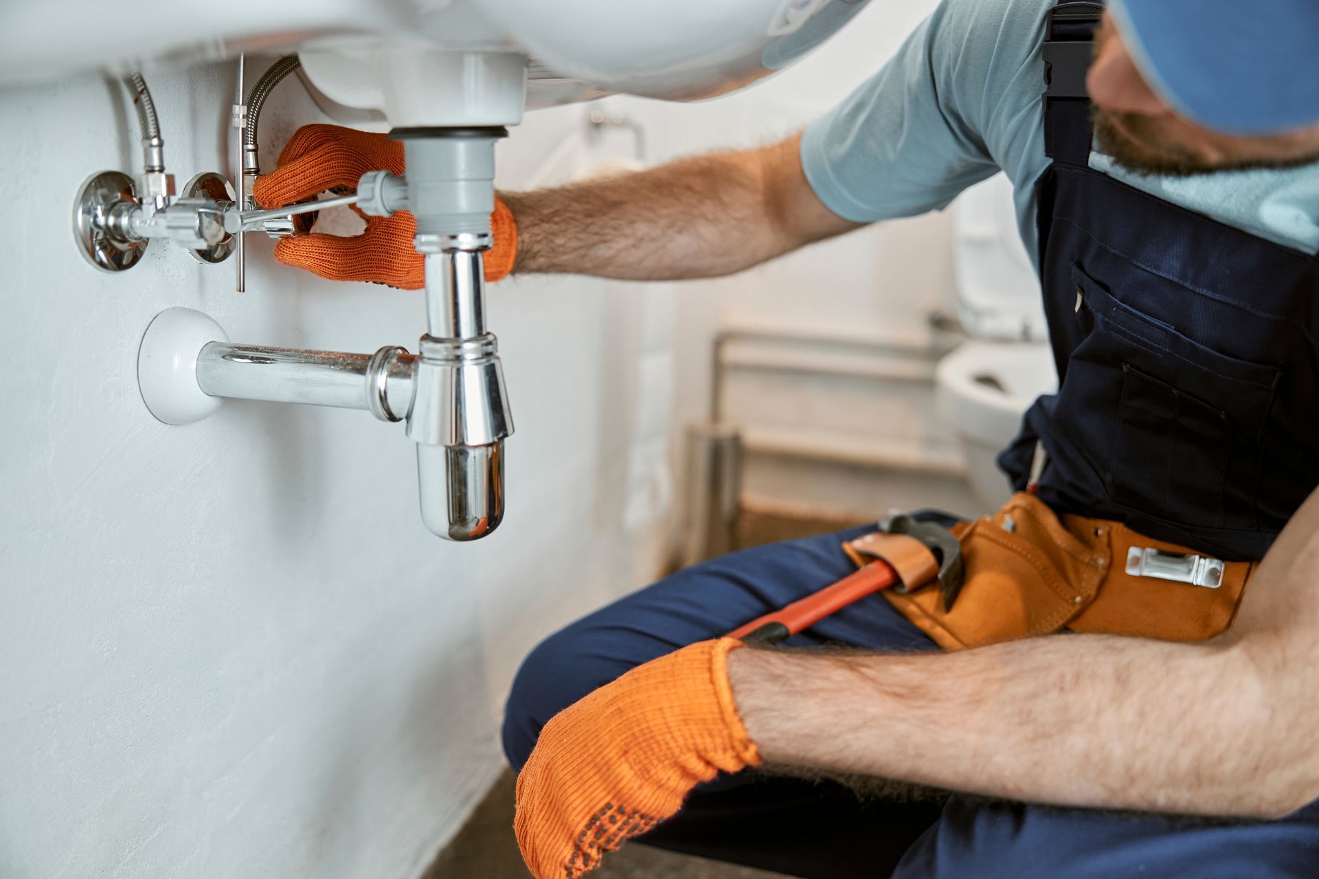 A plumber is fixing a sink in a bathroom.