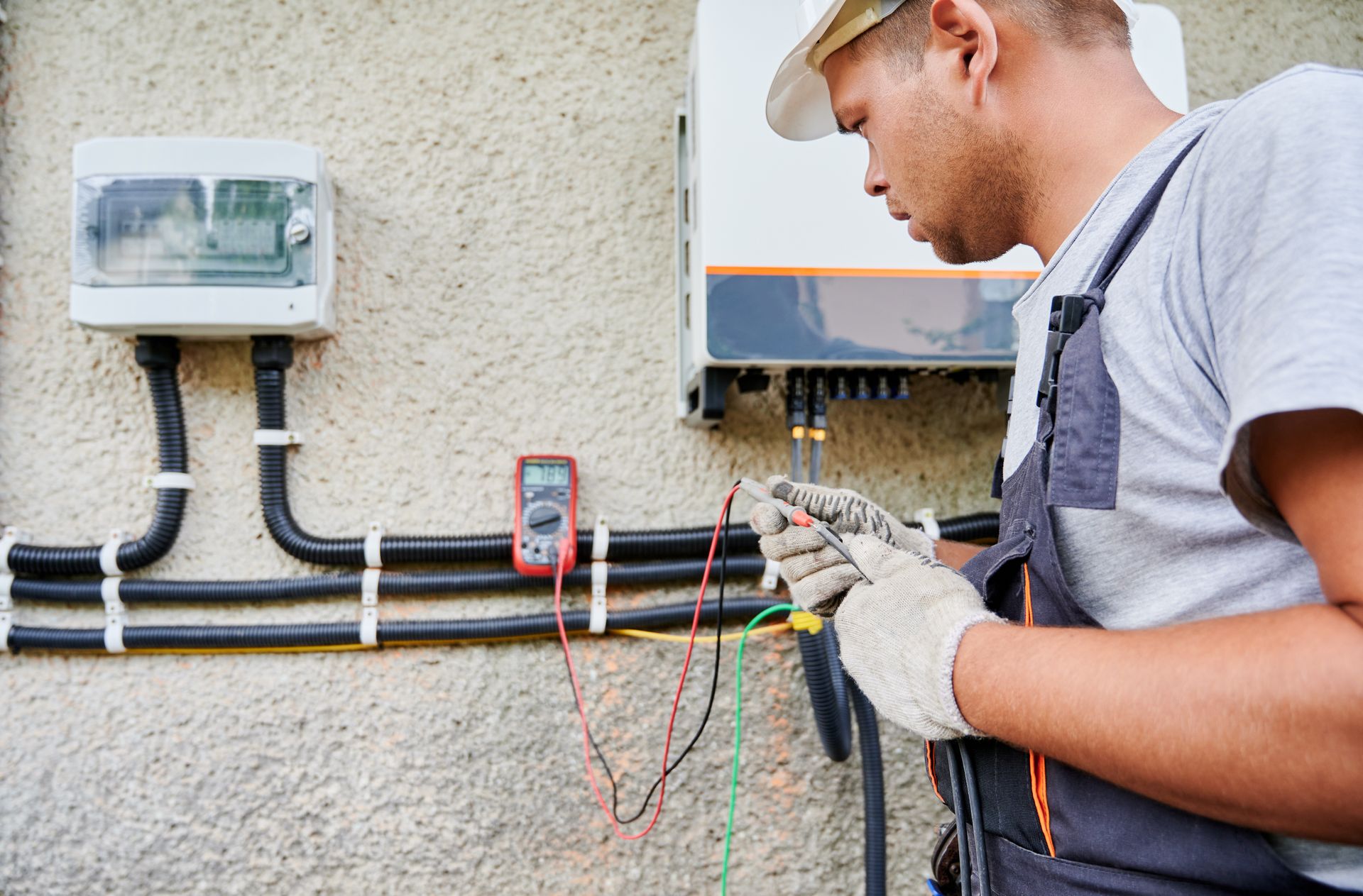 A man is working on a solar panel with a multimeter.