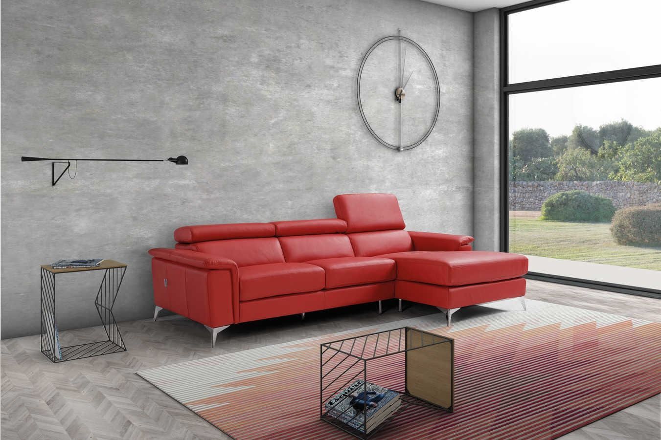 Divano componibile rosso in un soggiorno moderno con ampia finestra, orologio e tavolini laterali.