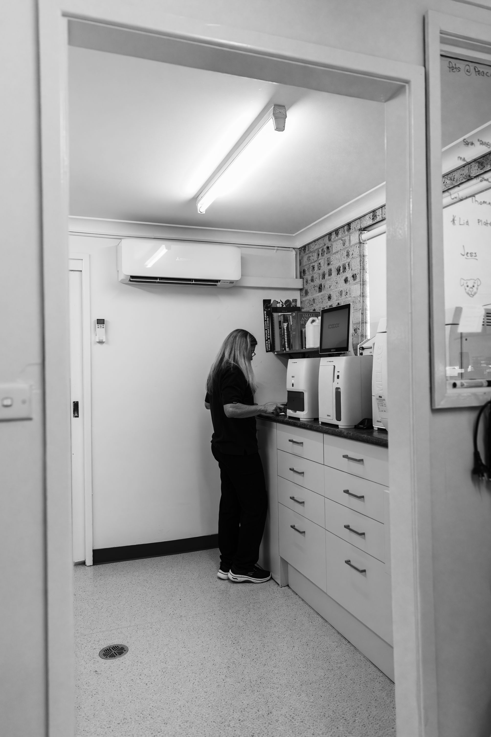 A black and white photo of a woman standing in a kitchen.