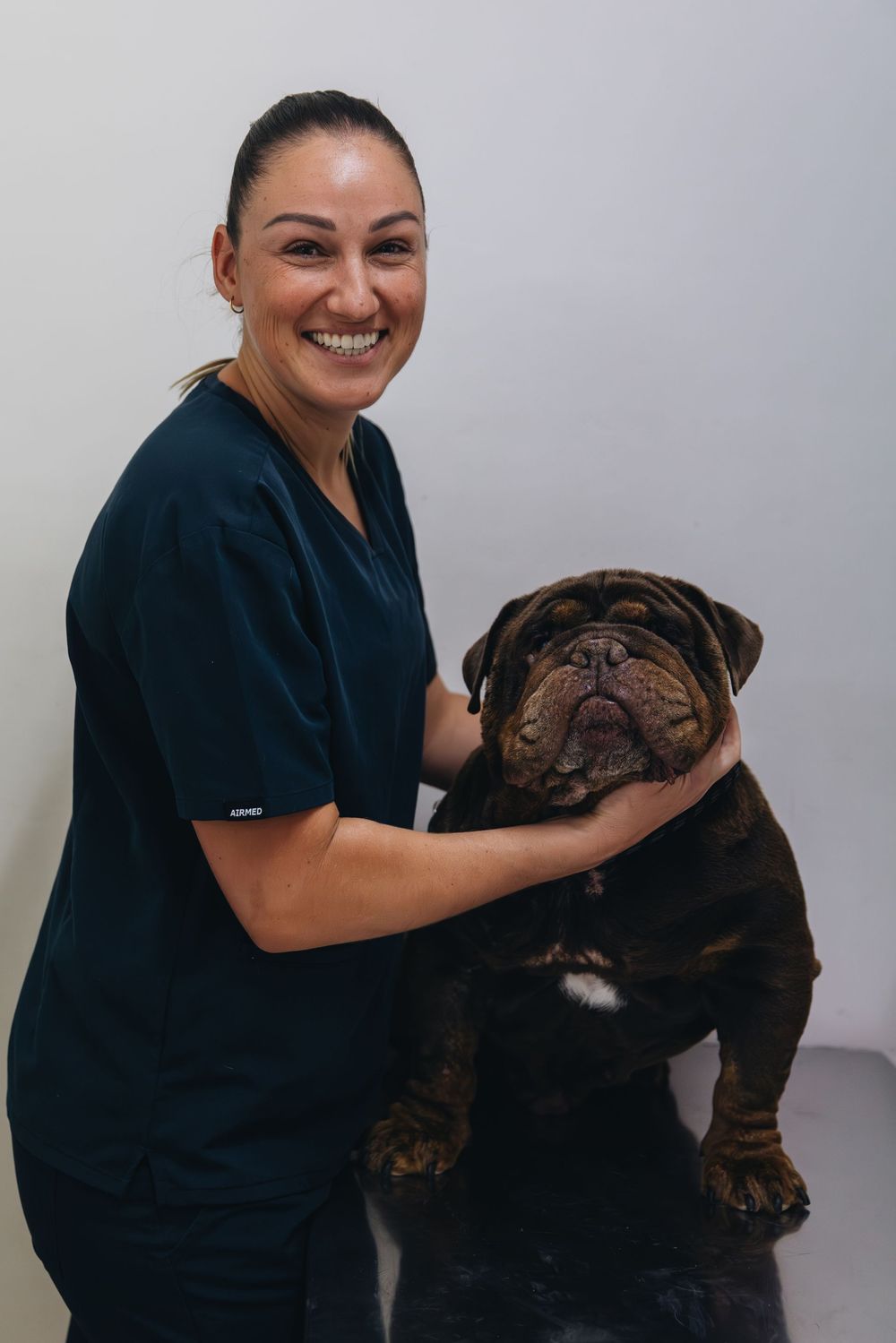 A woman is holding a brown dog in her arms.