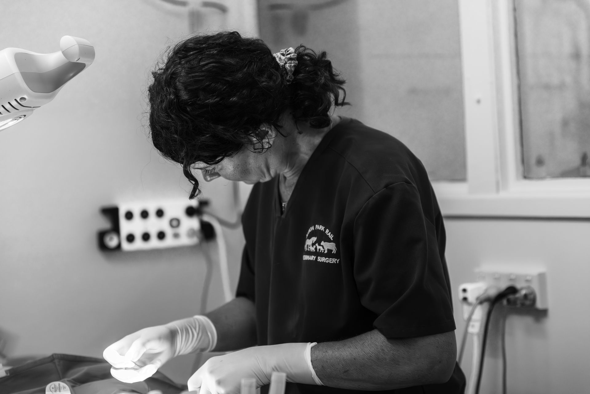 A black and white photo of a woman wearing scrubs and gloves.