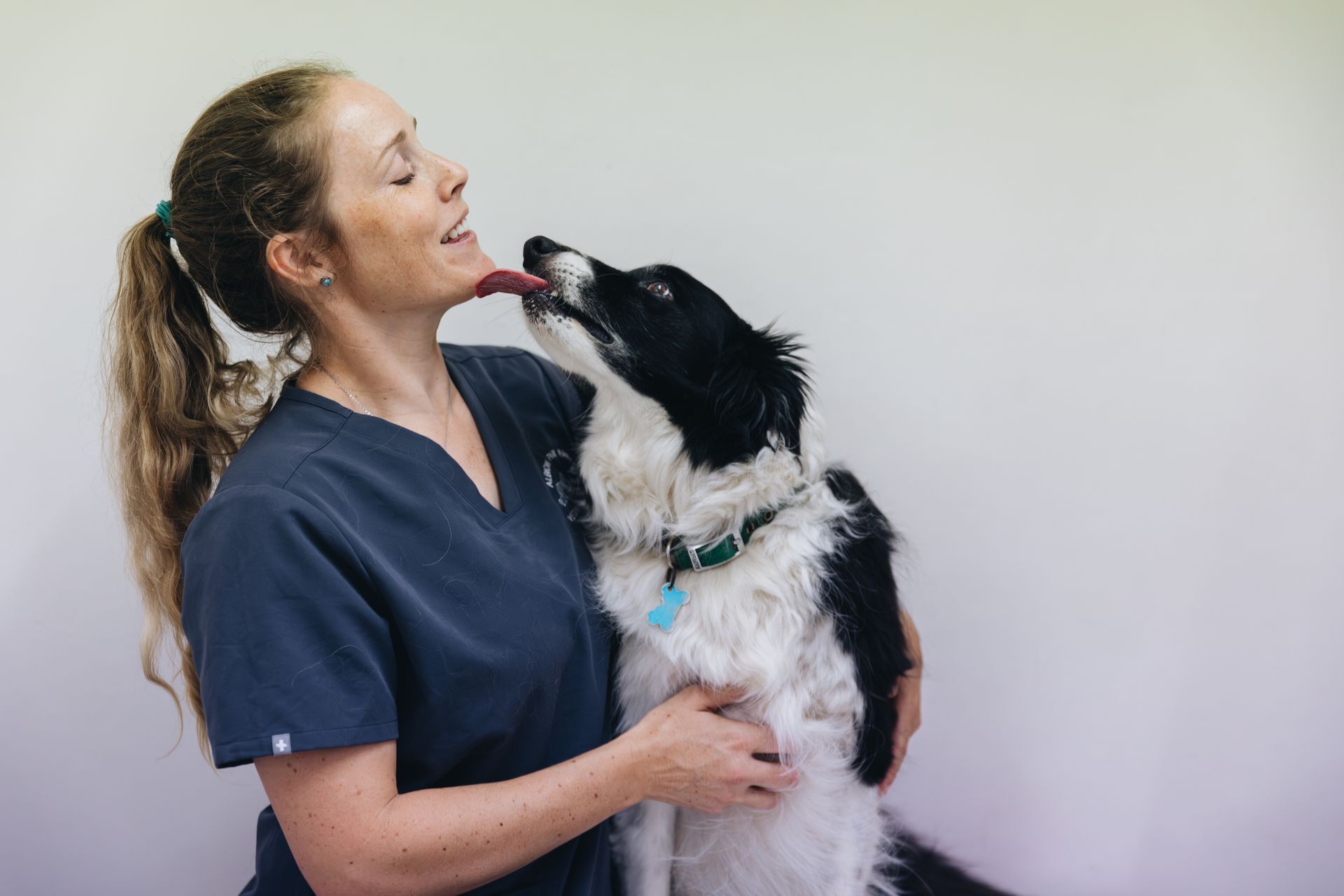 A woman is holding a black and white dog in her arms.