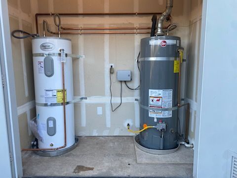 Two water heaters are sitting next to each other in a room.
