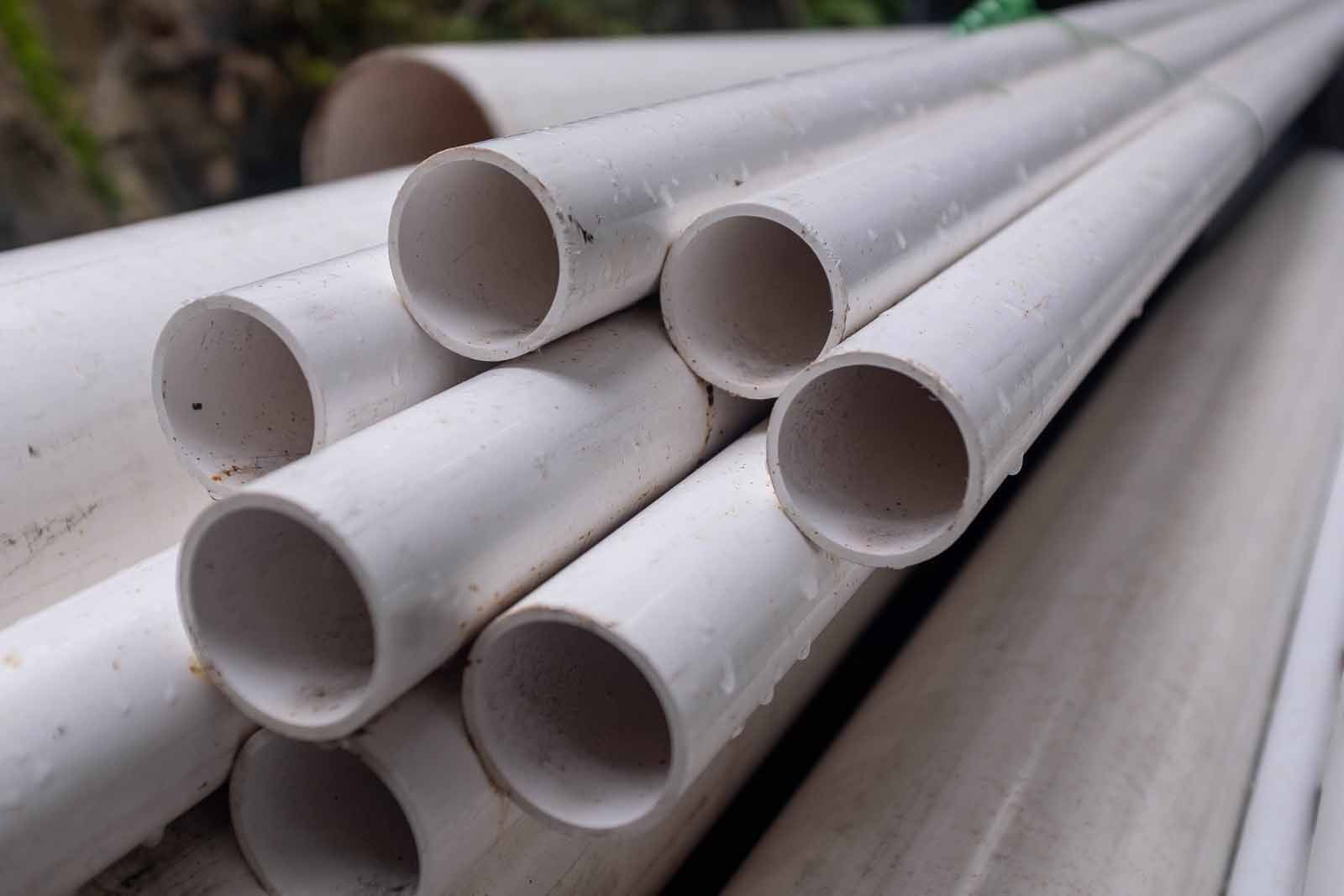 A bunch of white plastic pipes are stacked on top of each other.