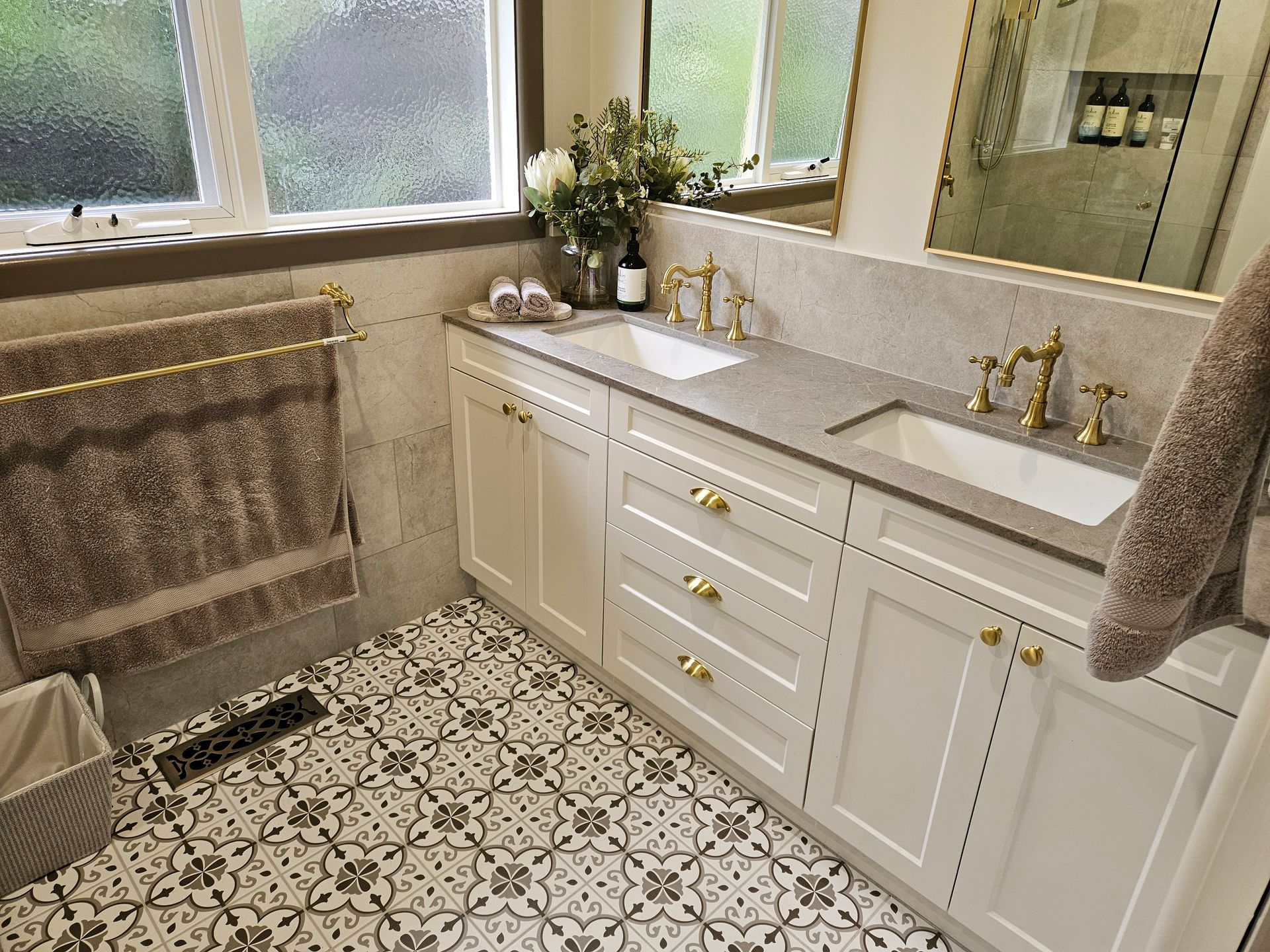 A bathroom with two sinks , a mirror and a window.