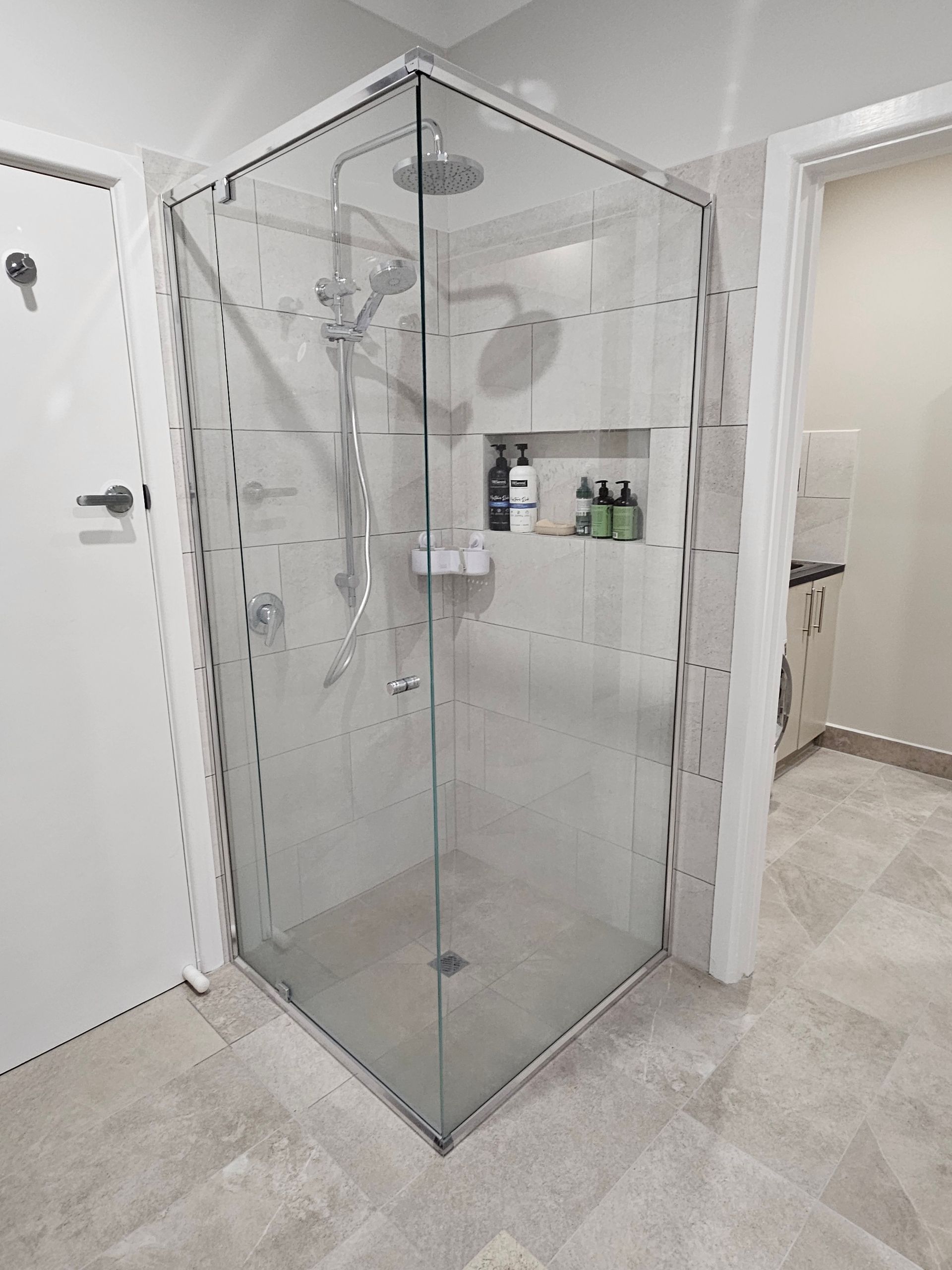 A bathroom with a shower stall with a glass door and a shower head.
