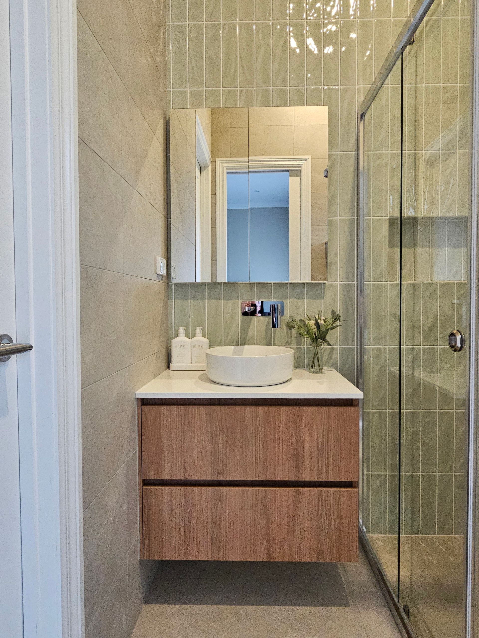 A bathroom with a sink , mirror and shower.