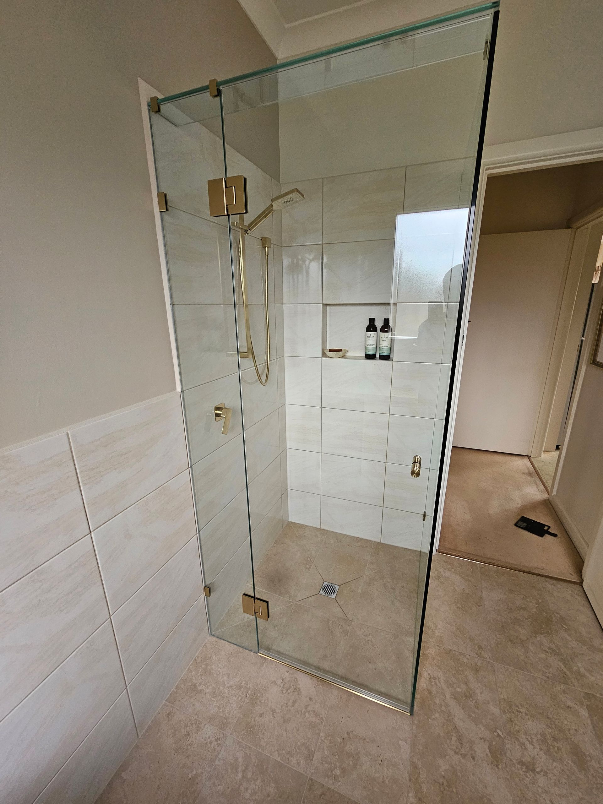 A bathroom with a walk in shower with a glass door