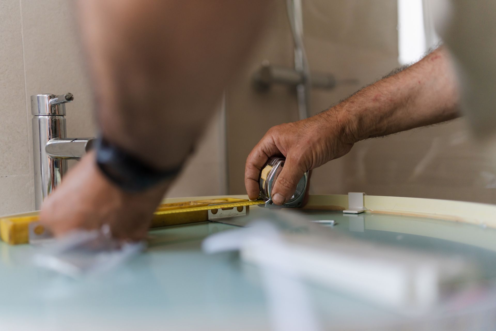 Close-up picture of a contractor taking measurements in a residential bathroom.