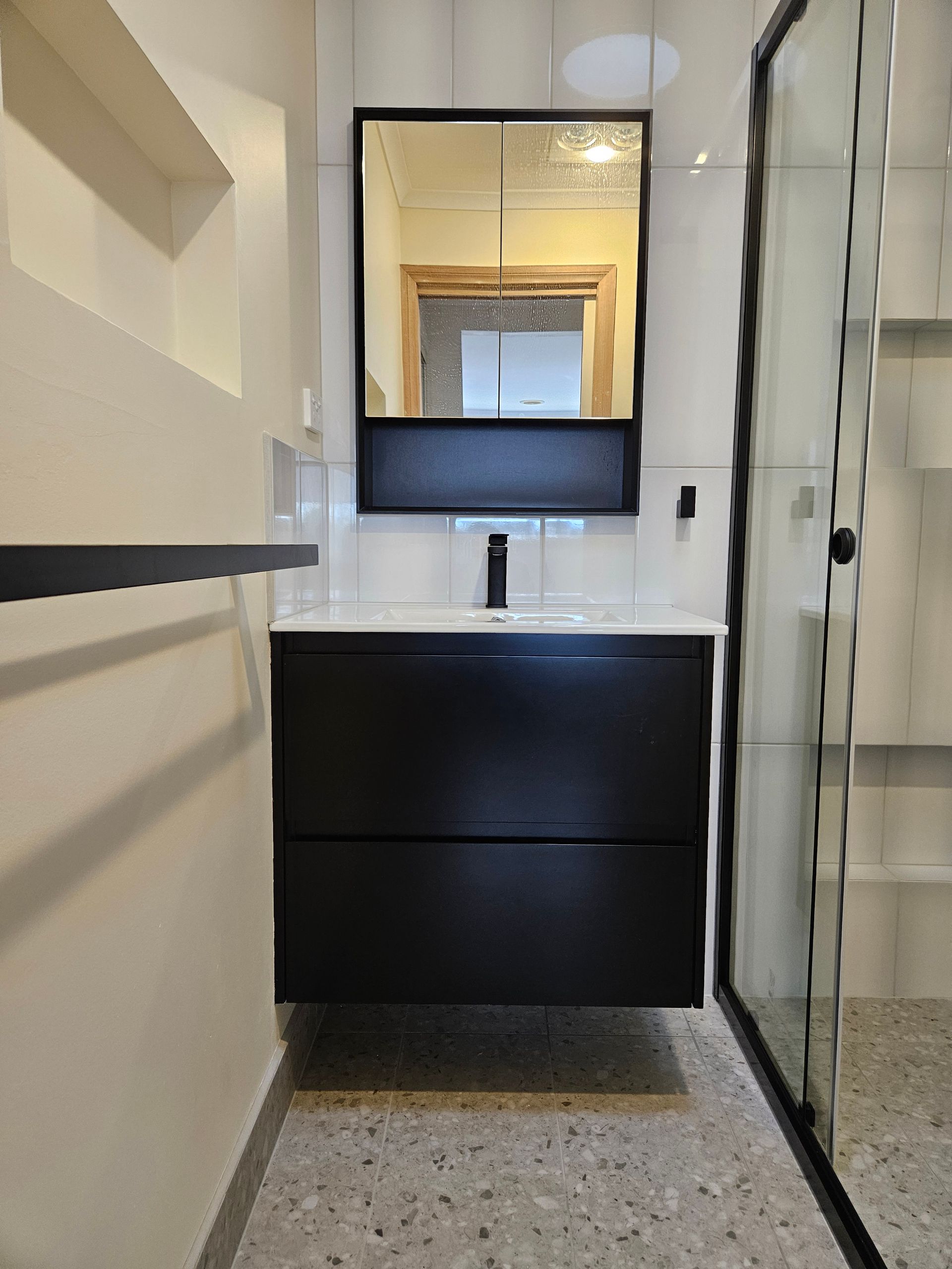 A bathroom with a sink , mirror and shower.