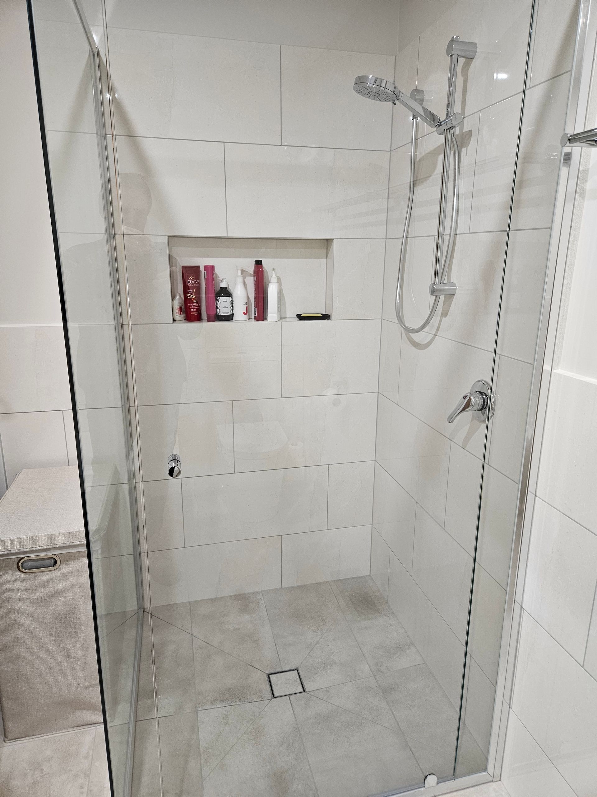 A bathroom with a walk in shower with a glass door.