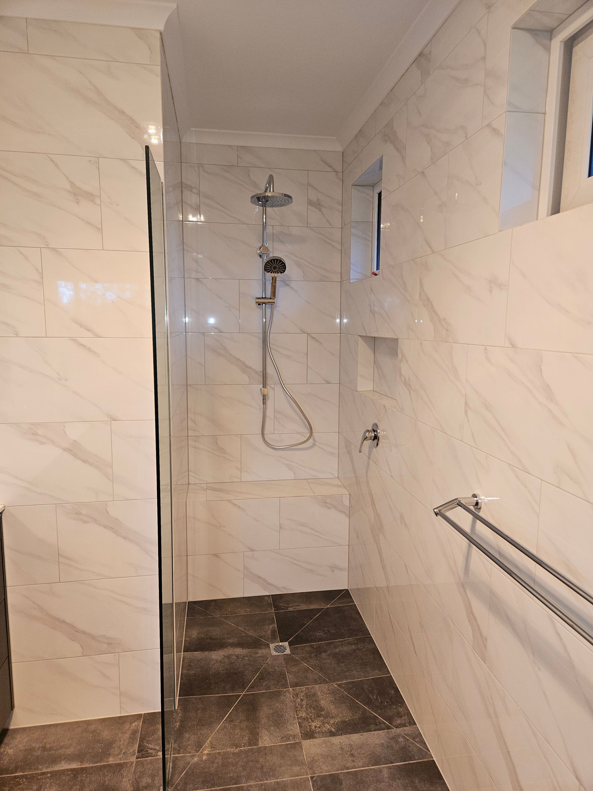 A bathroom with marble tiles and a walk in shower.