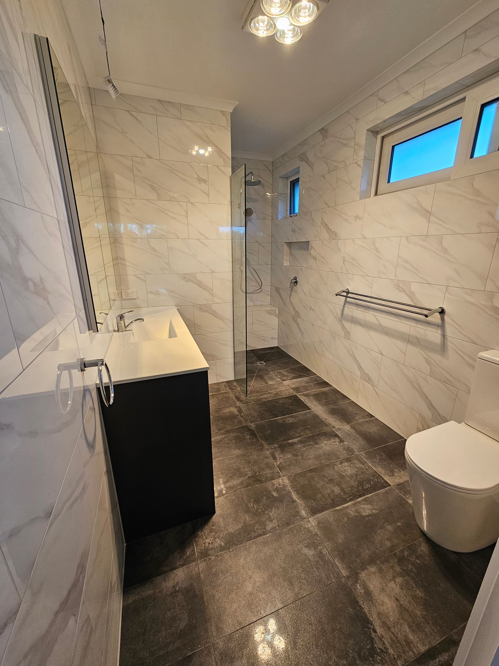 A bathroom with a toilet , sink and shower.