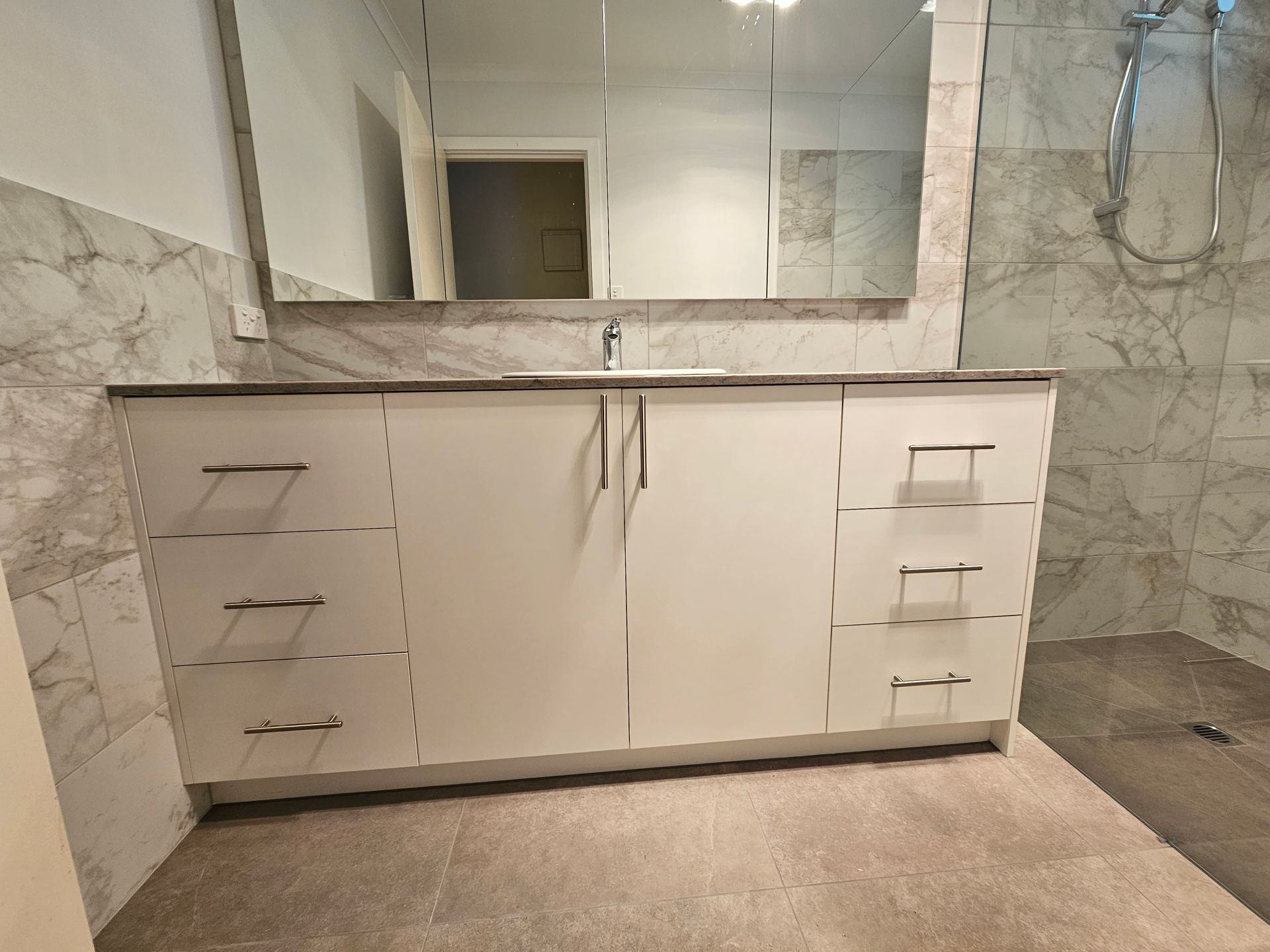 A bathroom with a sink , mirror and shower.