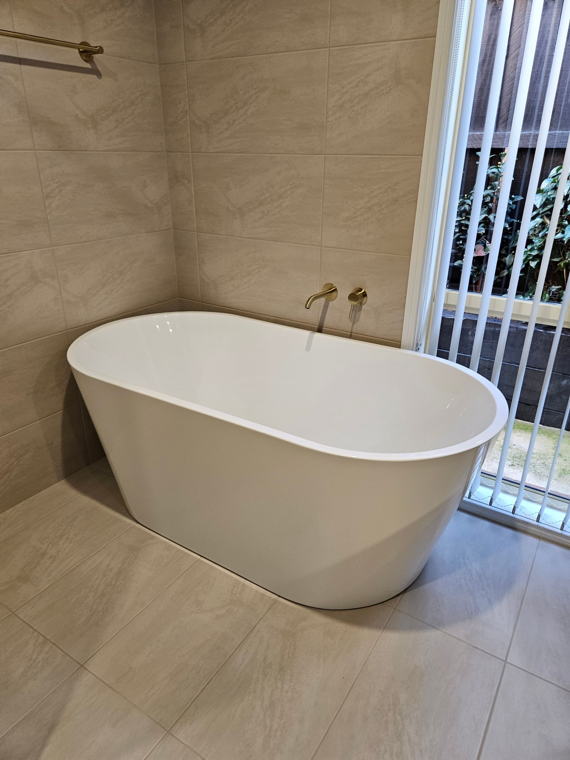 A white bathtub is sitting in a bathroom next to a window.