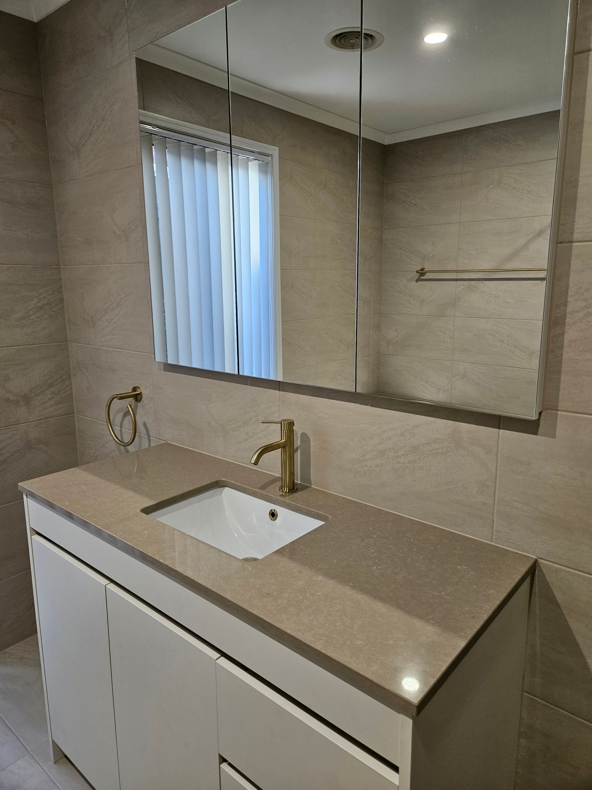 A bathroom with a sink , mirror and window.