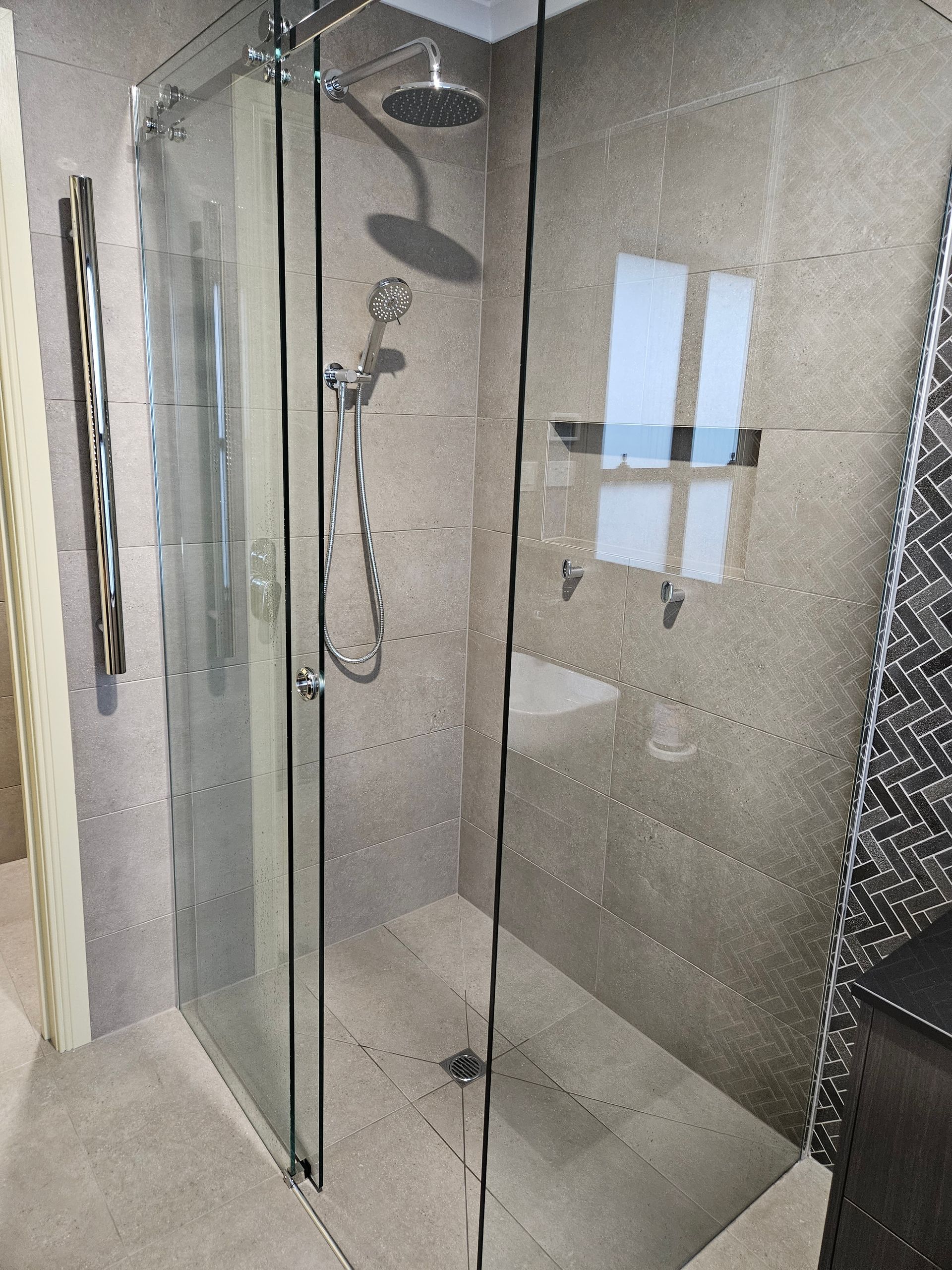 A bathroom with a walk in shower and a shower head.