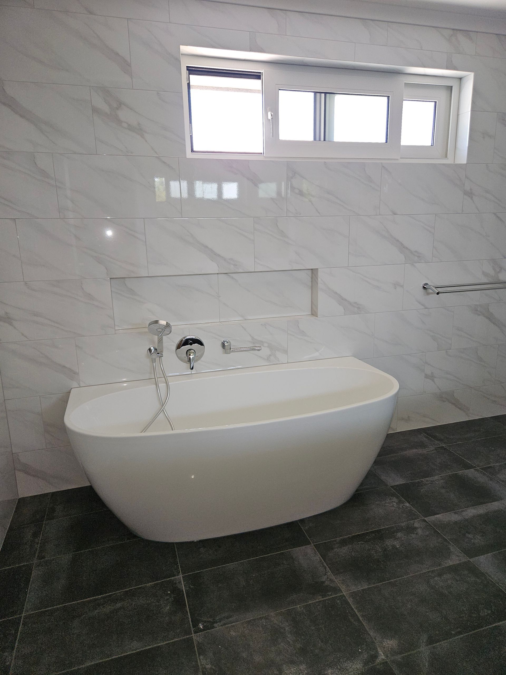 A bathtub is sitting in a bathroom next to a window.