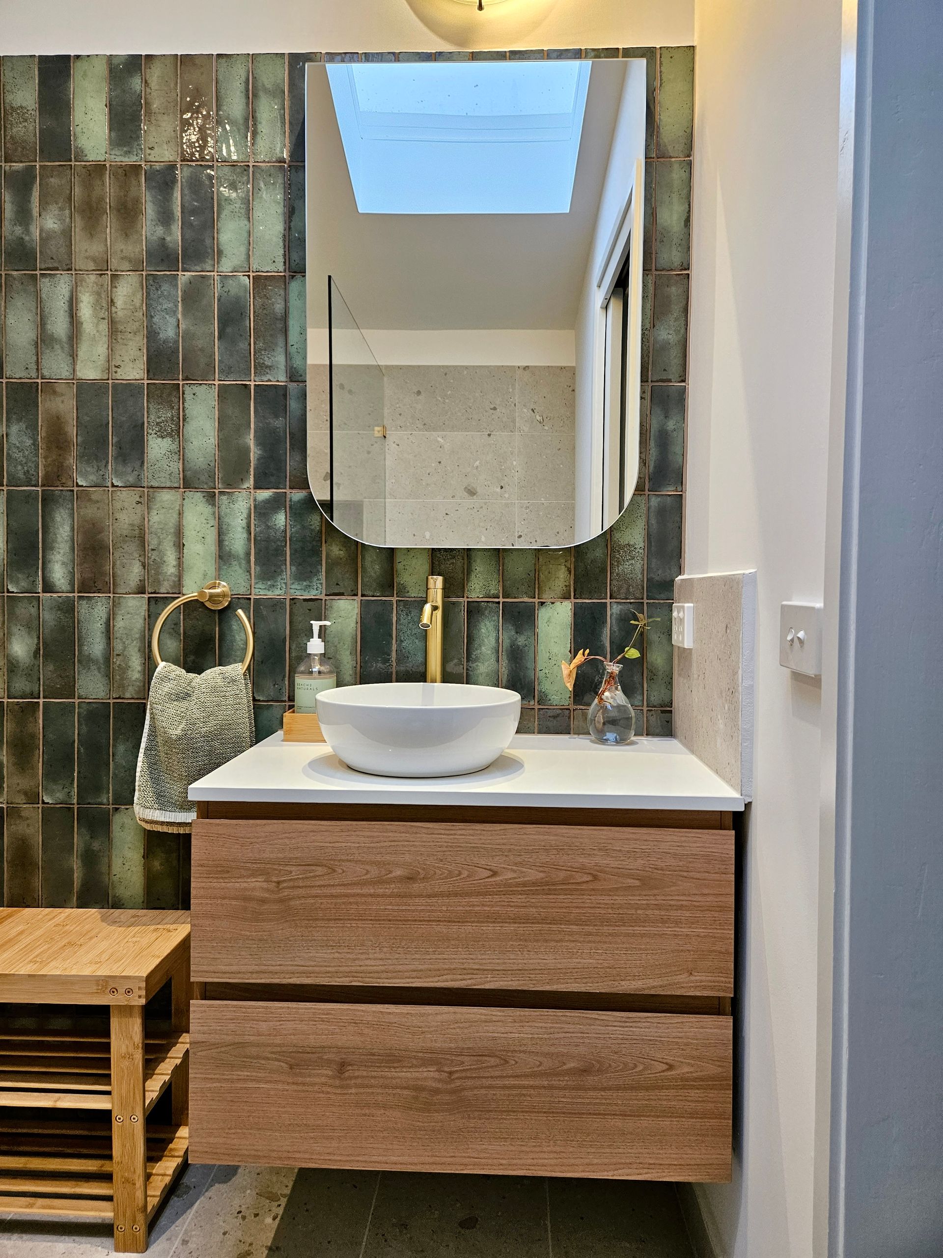 A bathroom with a sink , mirror and skylight.
