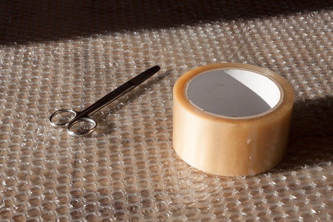 Scissors and a roll of clear packing tape on bubble wrap.