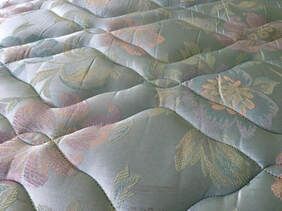 Close-up of a quilted mattress surface with a floral pattern in pastel colors.