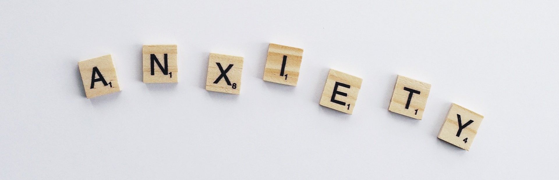 The word anxiety is written in scrabble tiles on a white background.