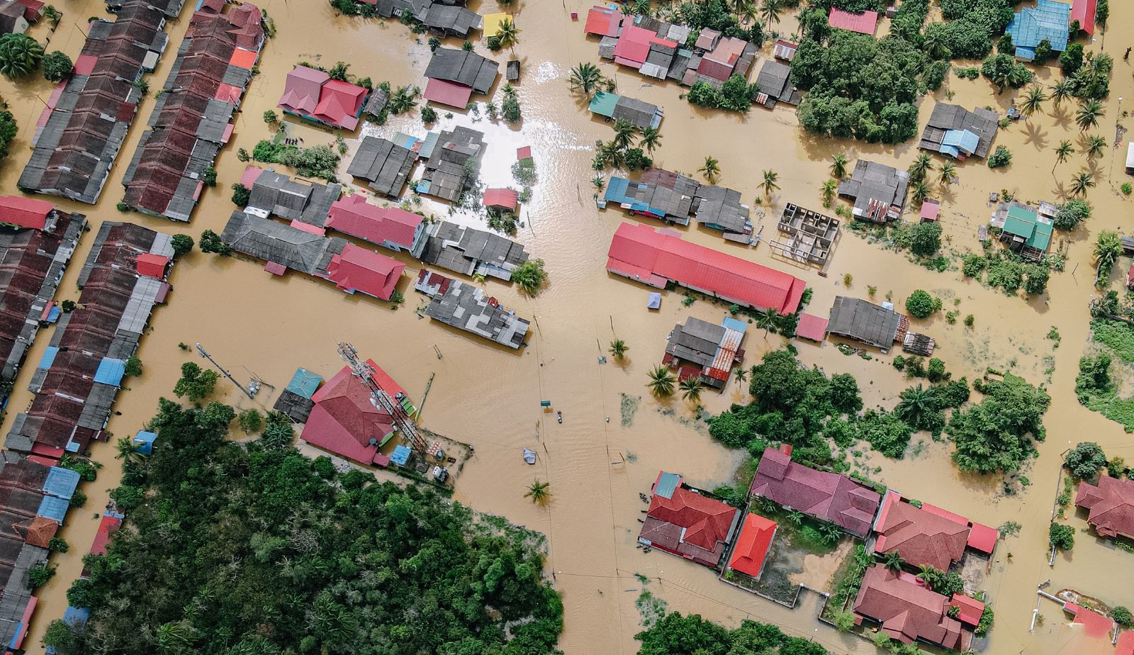 An aerial view of a flooded city with houses and trees covered in water.