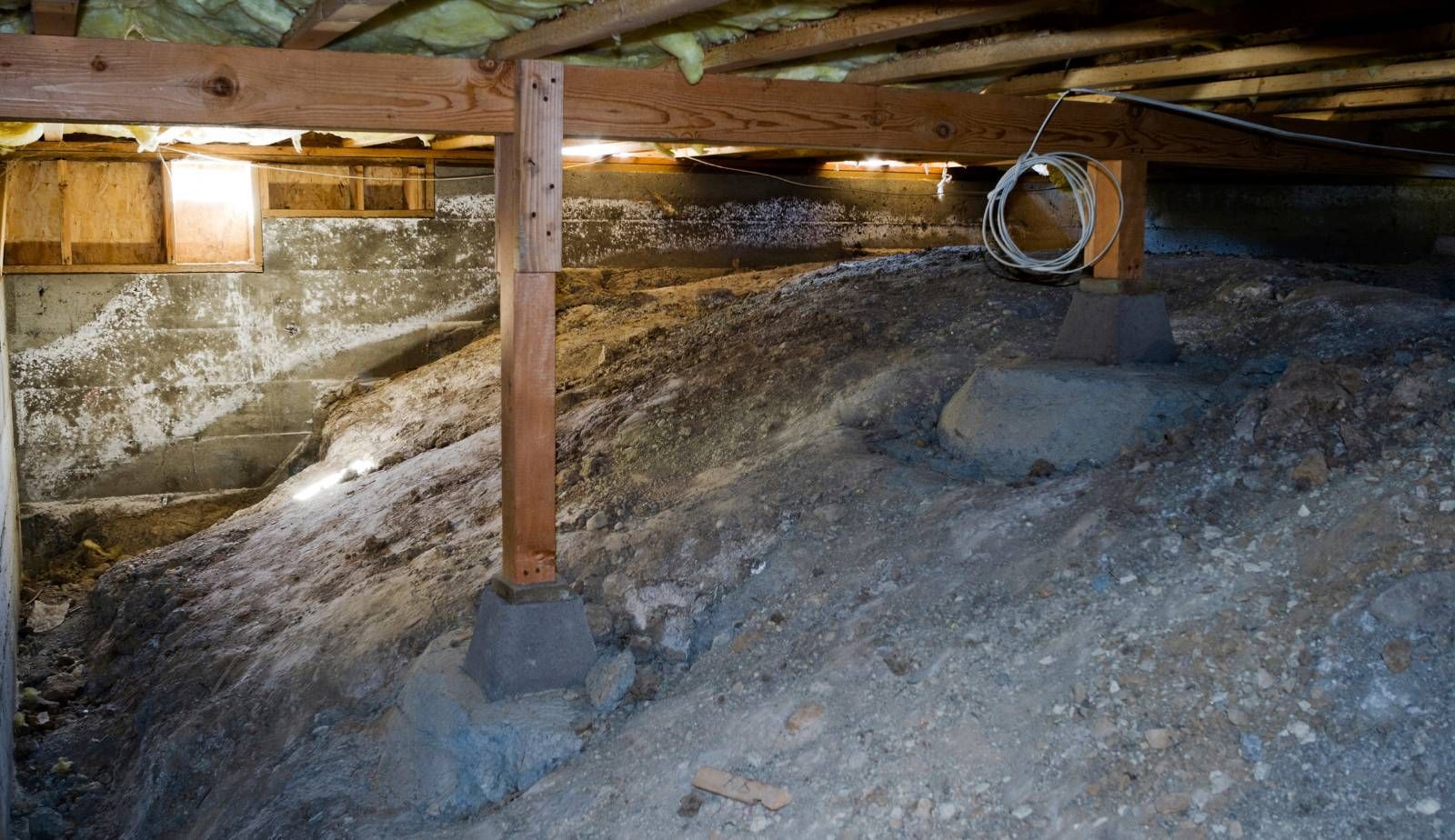 Visible moisture damage on wooden joists and insulation inside a humid Louisiana crawl space, illustrating the long-term risks of trapped moisture.