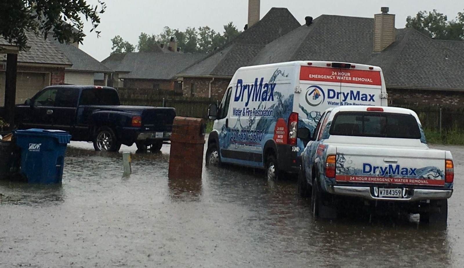 Drymax technicians using drying equipment in a water-damaged lower-level room of a Louisiana home, responding to flash flood damage.