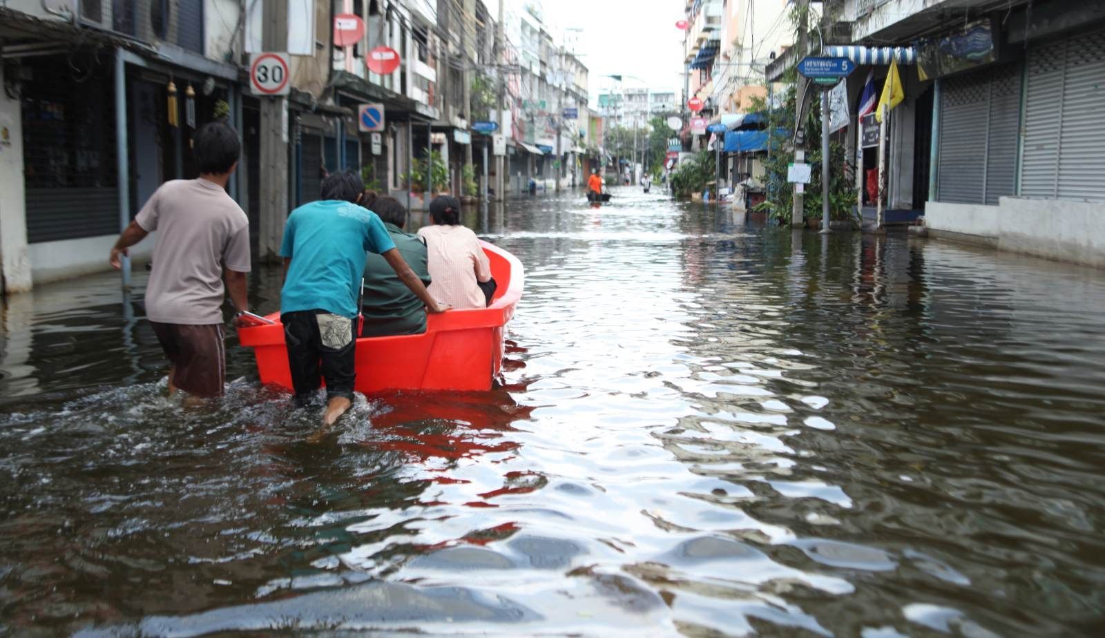 A residential Louisiana street submerged after a flash flood, with rising water approaching homes.