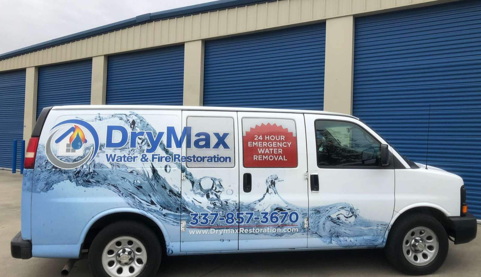 A drymax van is parked in front of a building.