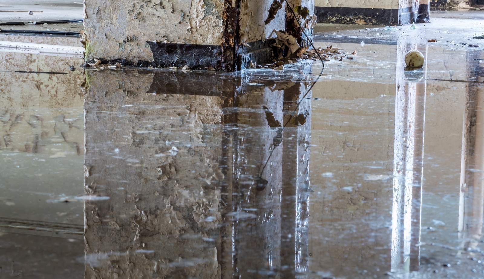 Professional restoration technicians using powerful water extraction equipment to remove standing water from a flooded kitchen, demonstrating immediate water removal actions.