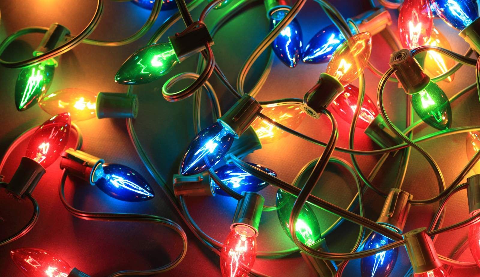 A bunch of colorful christmas lights are hanging from a string.