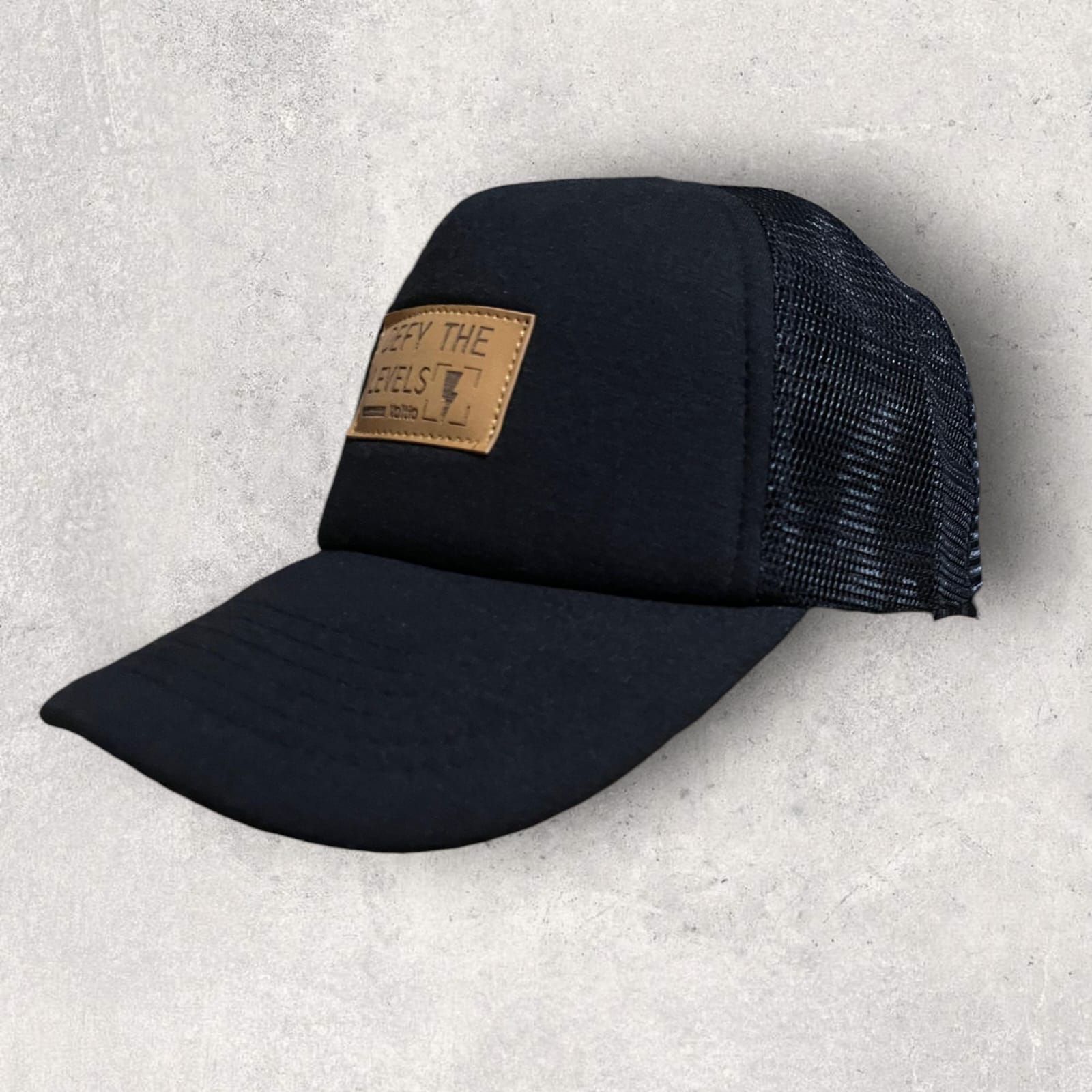 Gorra de camionero negra con un parche de cuero que dice 