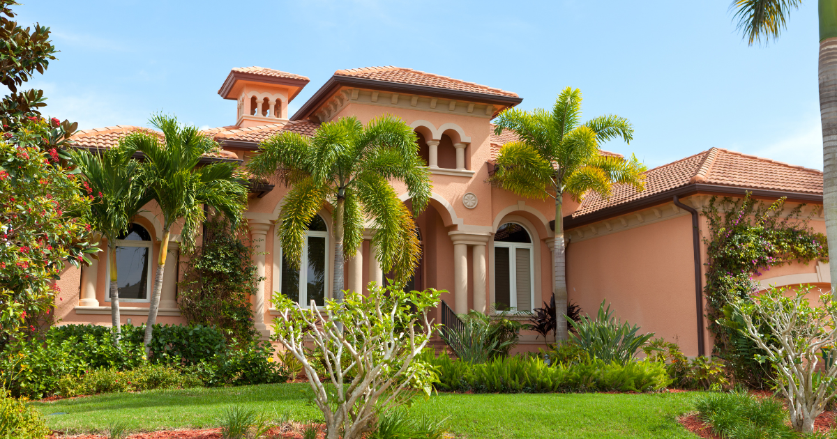 Mediterranean-style villa with arched windows, palm trees, and lush green landscaping