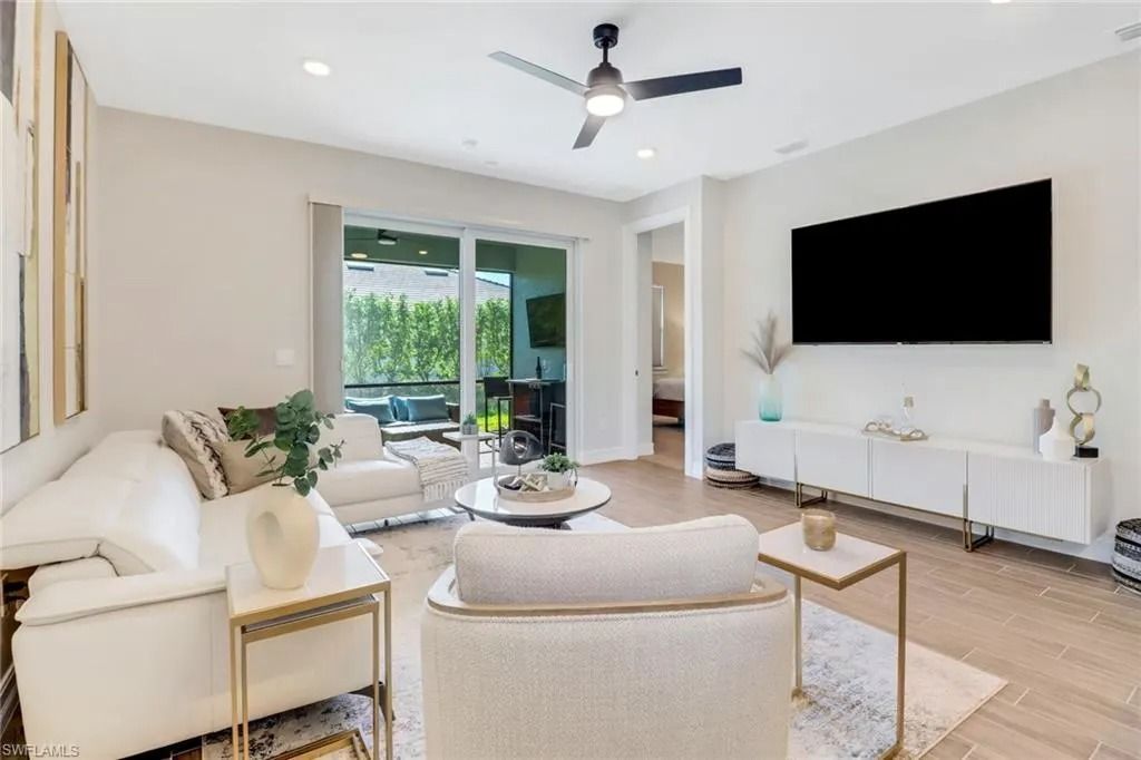 Modern living room with beige sofas, wall-mounted TV, and sliding glass doors to a patio