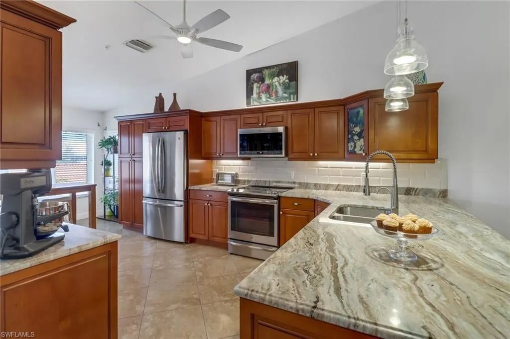 Modern kitchen with wood cabinets, stainless appliances, granite island, and a ceiling fan