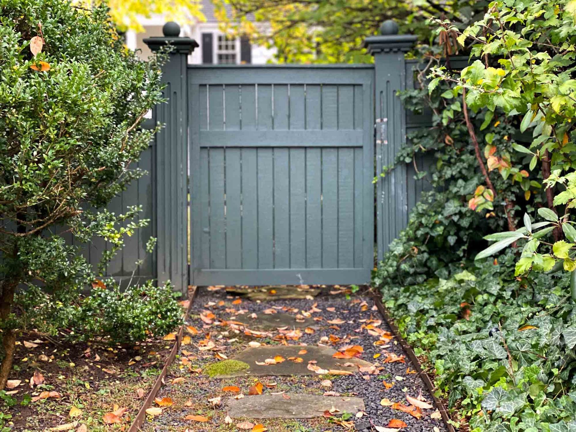 A Wooden Gate Is Surrounded by Trees and Bushes in A Garden | Cranbourne, VIC | Cranbourne Fencing Pty Ltd