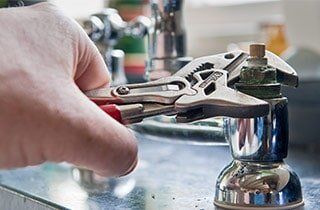 A person is fixing a faucet with a wrench.
