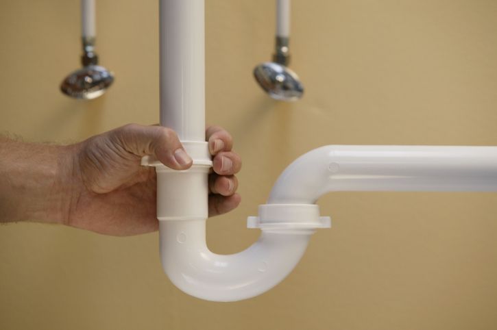 Skilled technician adjusting plumbing pipe for reliable drain cleaning company solutions.