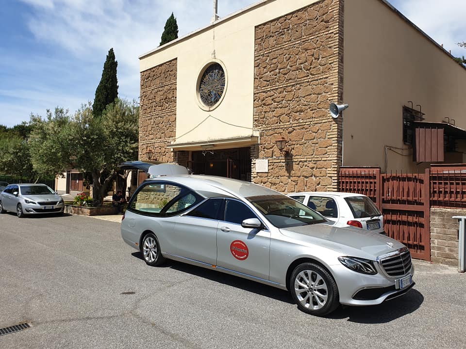 auto funebre con cofano aperto fuori da una chiesa