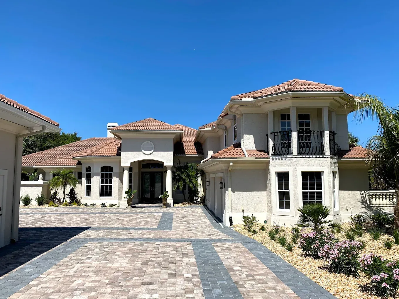 A large white house with a brick driveway leading to it.