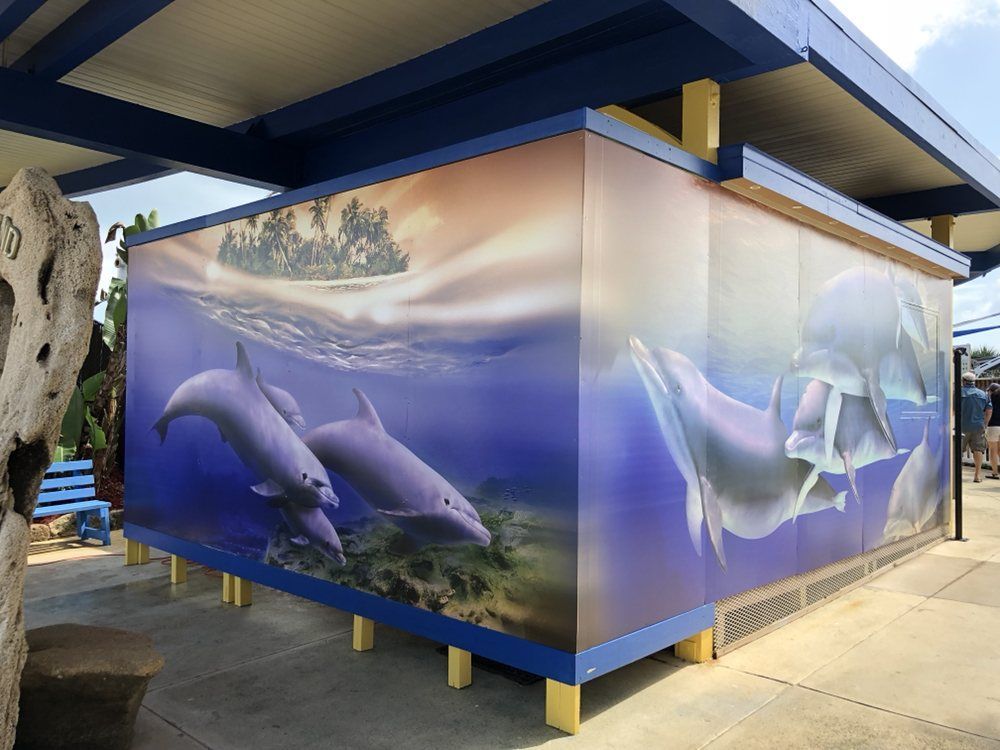 A painting of dolphins is on the side of a building.