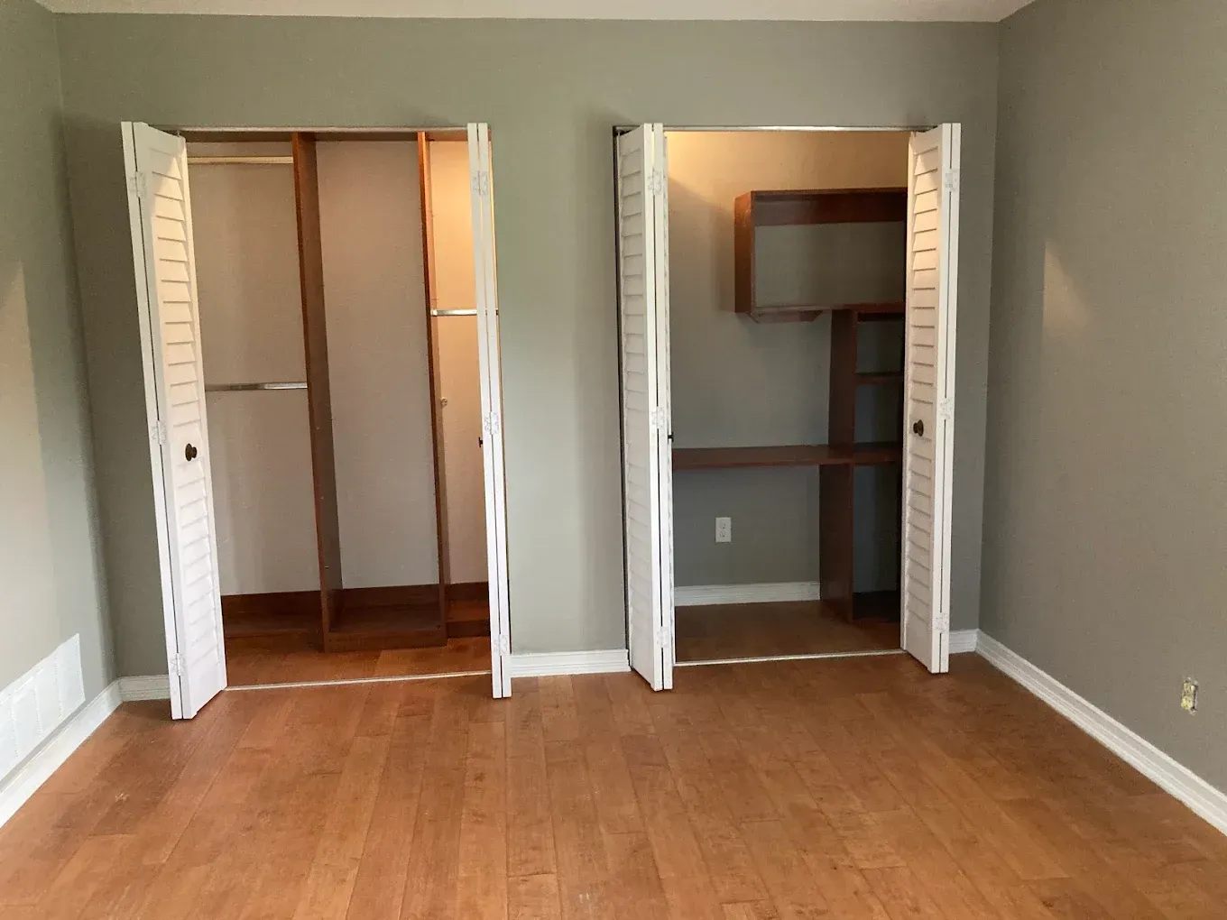 An empty room with two closets and a bookshelf