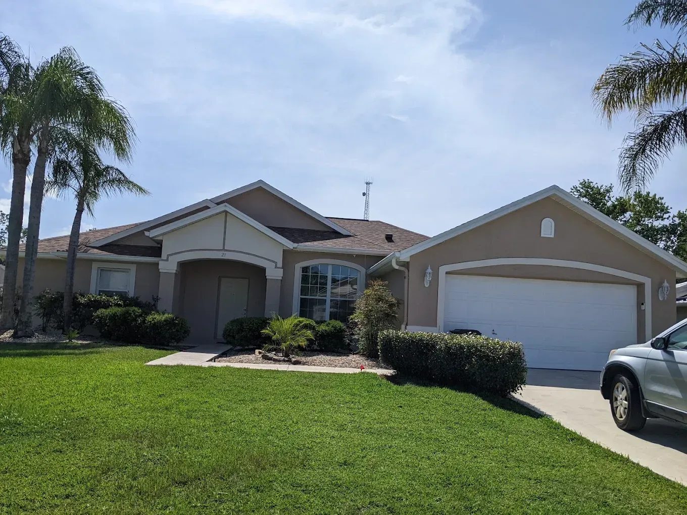 A car is parked in front of a house with a white garage door.