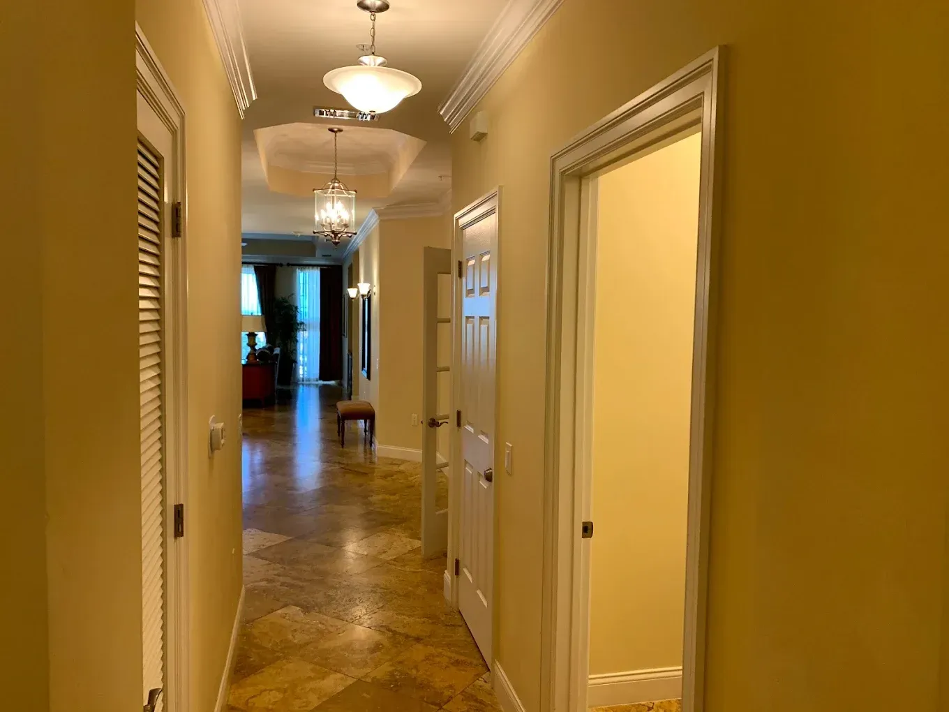 A long hallway in a house with a chandelier hanging from the ceiling.