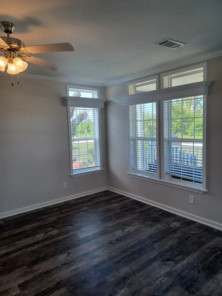 An empty living room with hardwood floors and a ceiling fan.