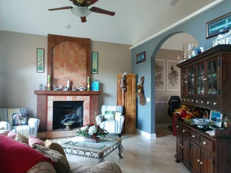 A living room with a fireplace and a ceiling fan