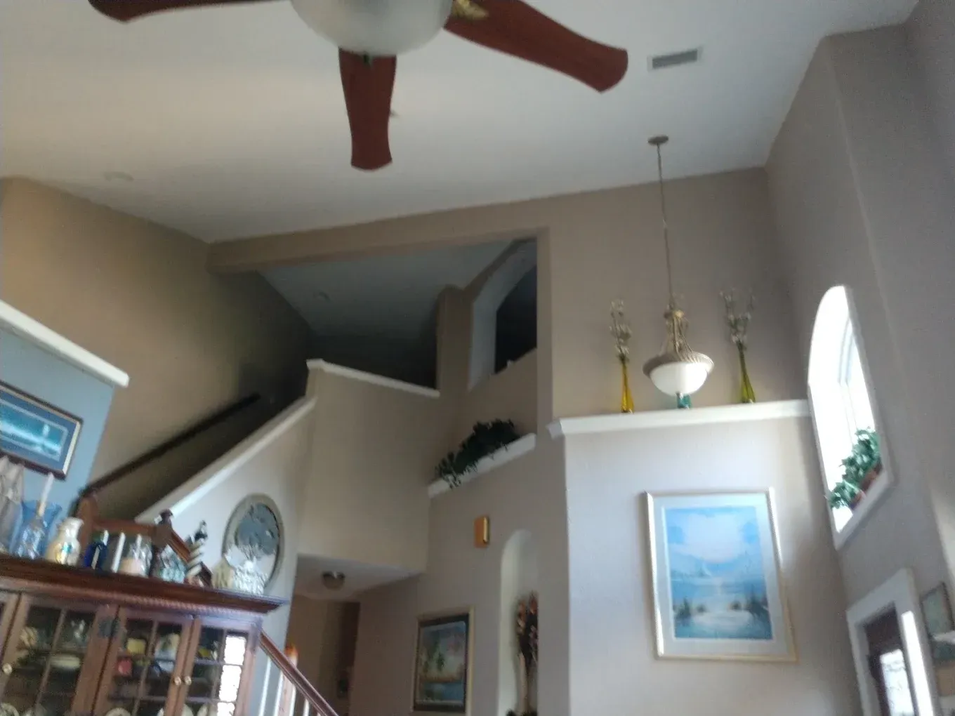 A living room with a ceiling fan and stairs